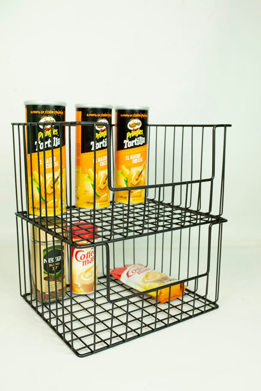 Vertical shot of an organized pantry shelf with snacks and canned beverages in a wire basket