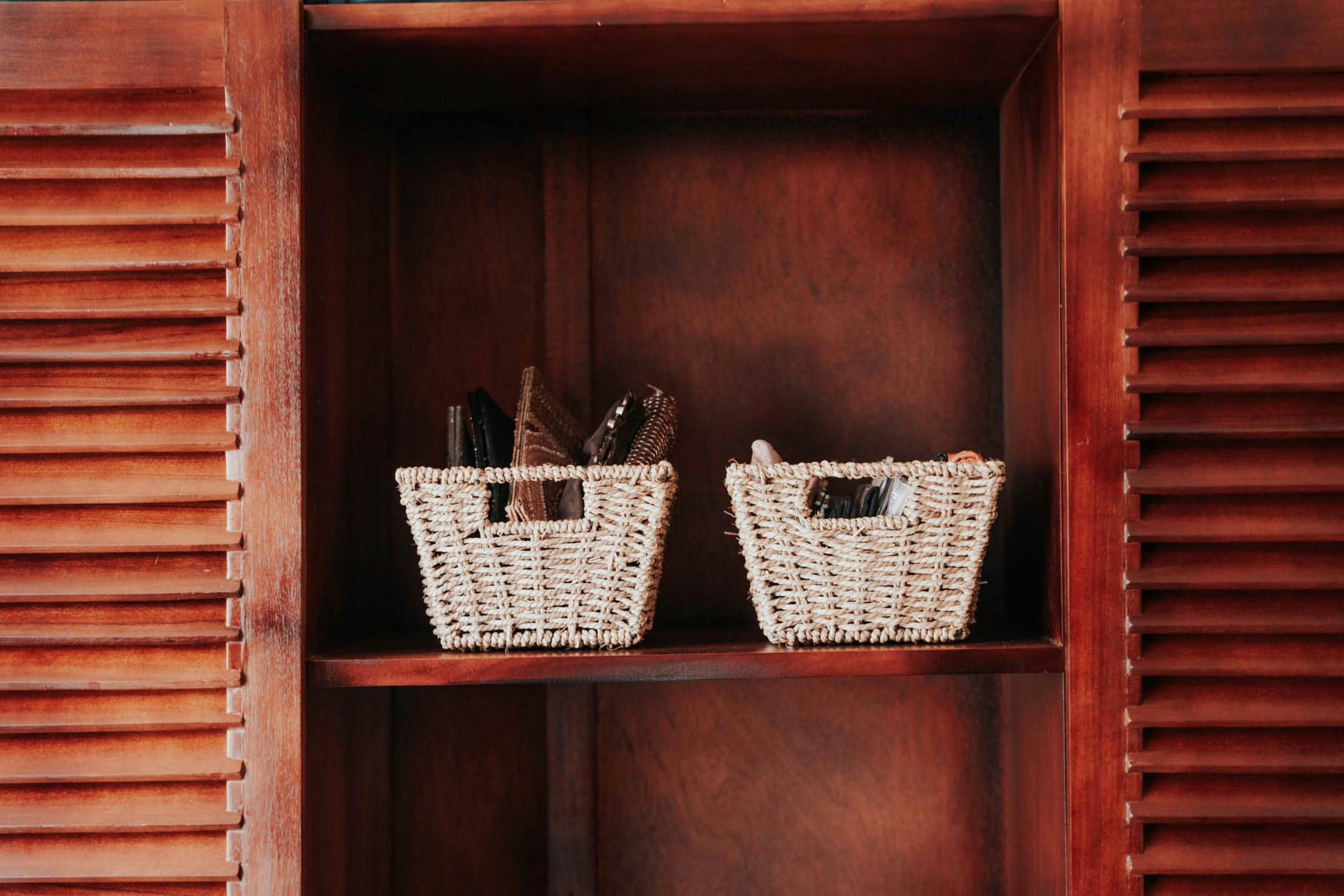 Two woven baskets on a wooden shelf within a cabinet, providing storage decor.