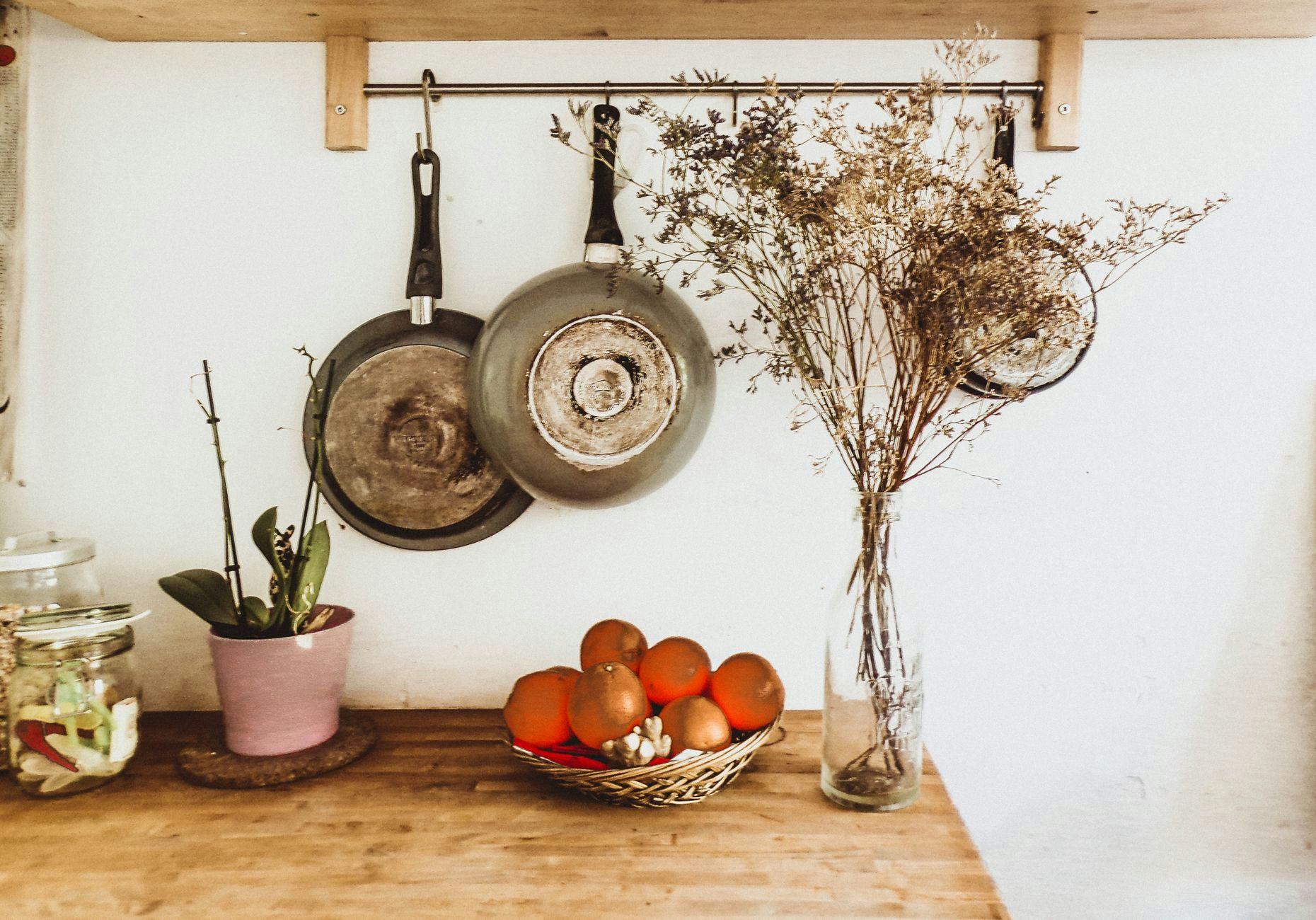 A cozy, rustic kitchen setup with hanging pans and wooden decor in an organized interior space.