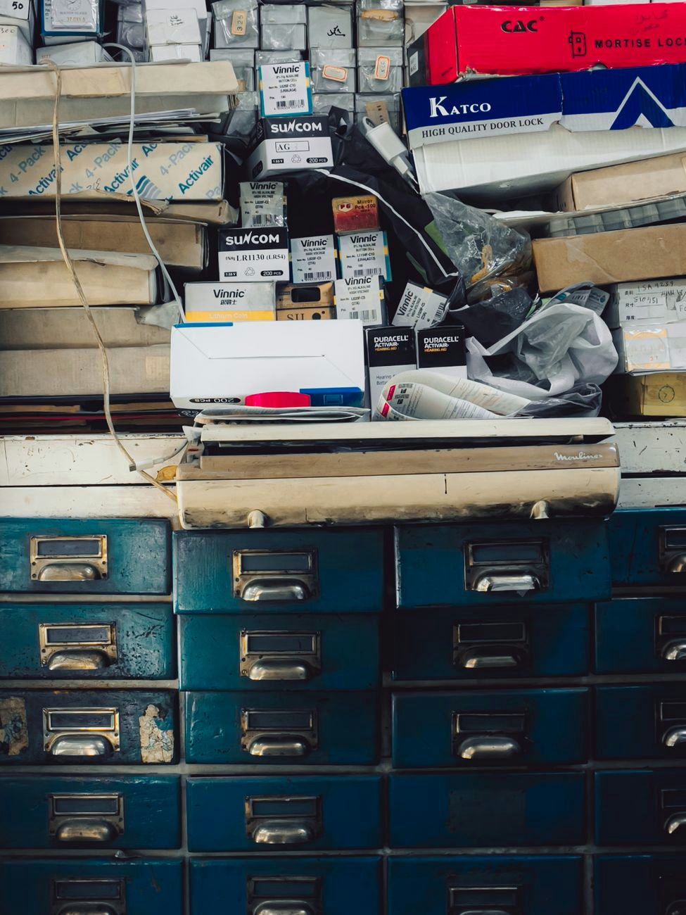 A cluttered vintage cabinet filled with assorted boxes and supplies in an indoor setting.