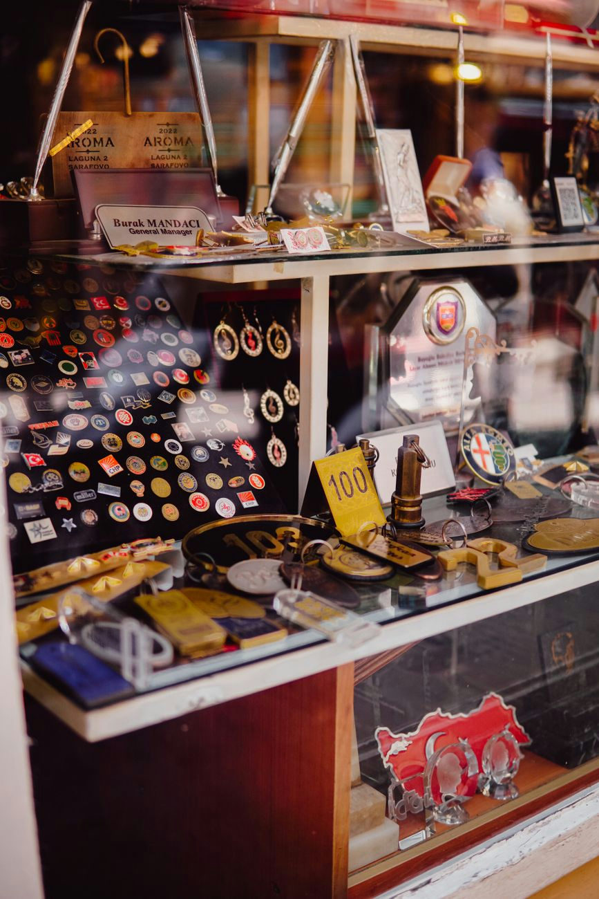 A diverse array of vintage pins, badges, and collectible items on display in a store window.