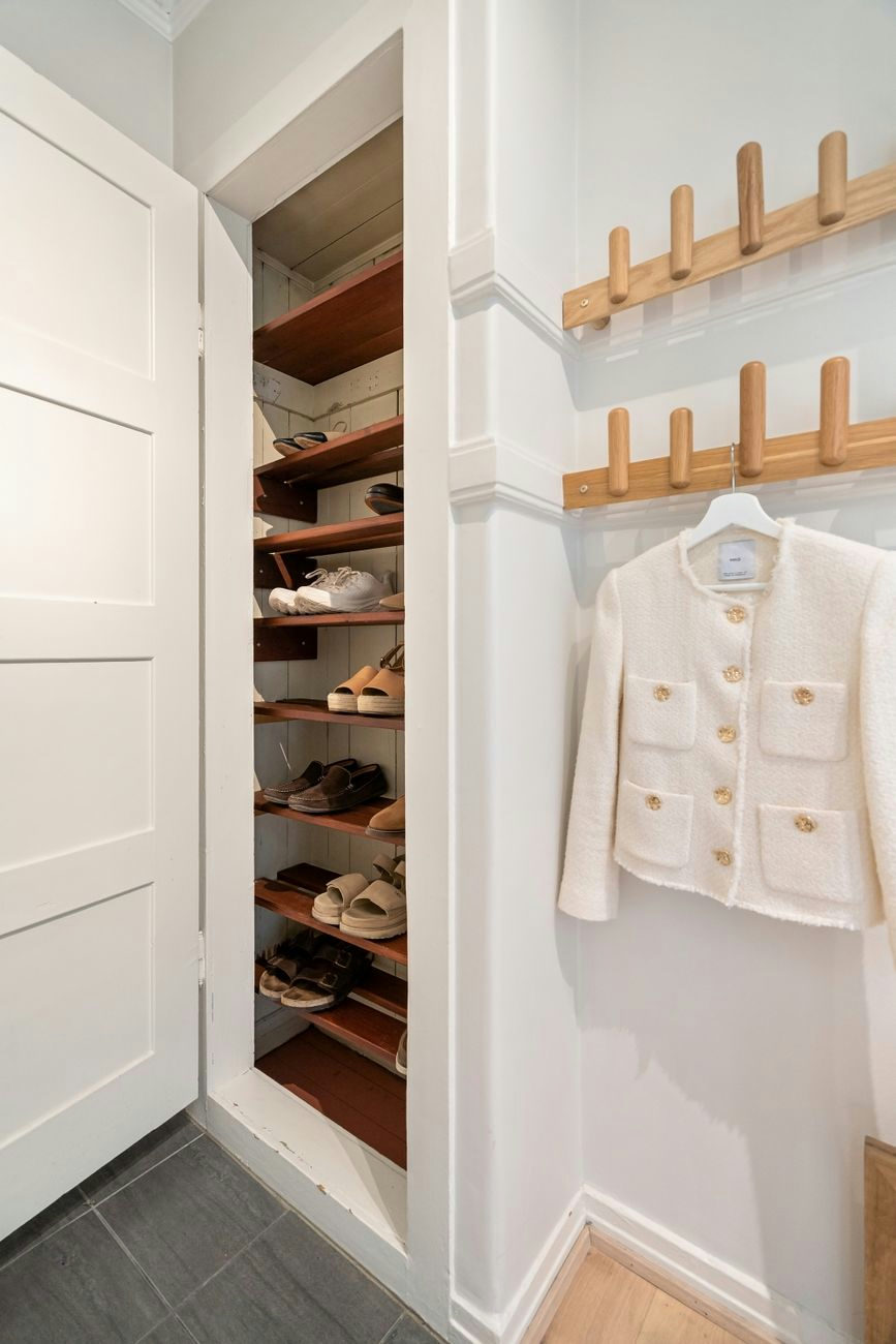 Contemporary closet scene with organized shoe storage and elegant coat rack.