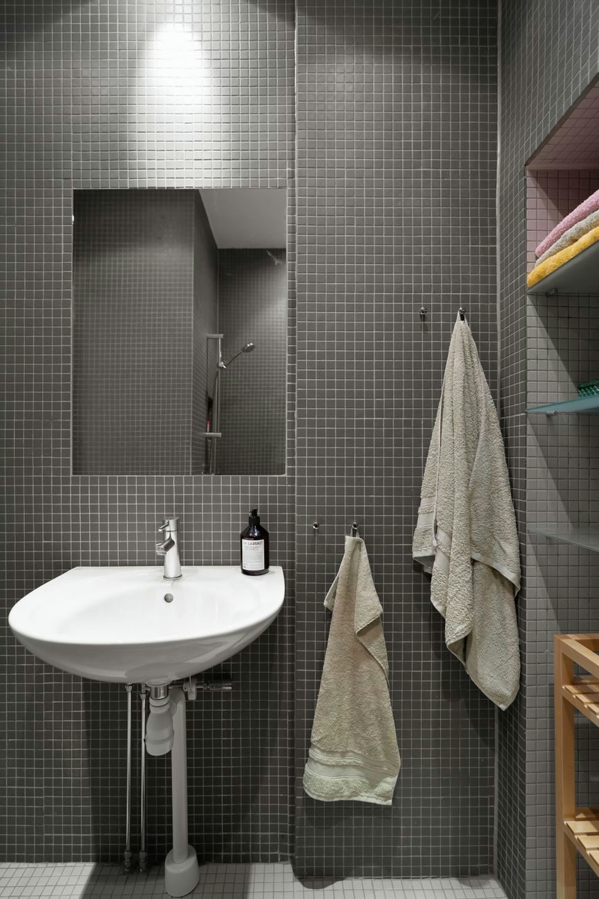 Elegant minimalist bathroom featuring a sink, mirror, and gray tiles.