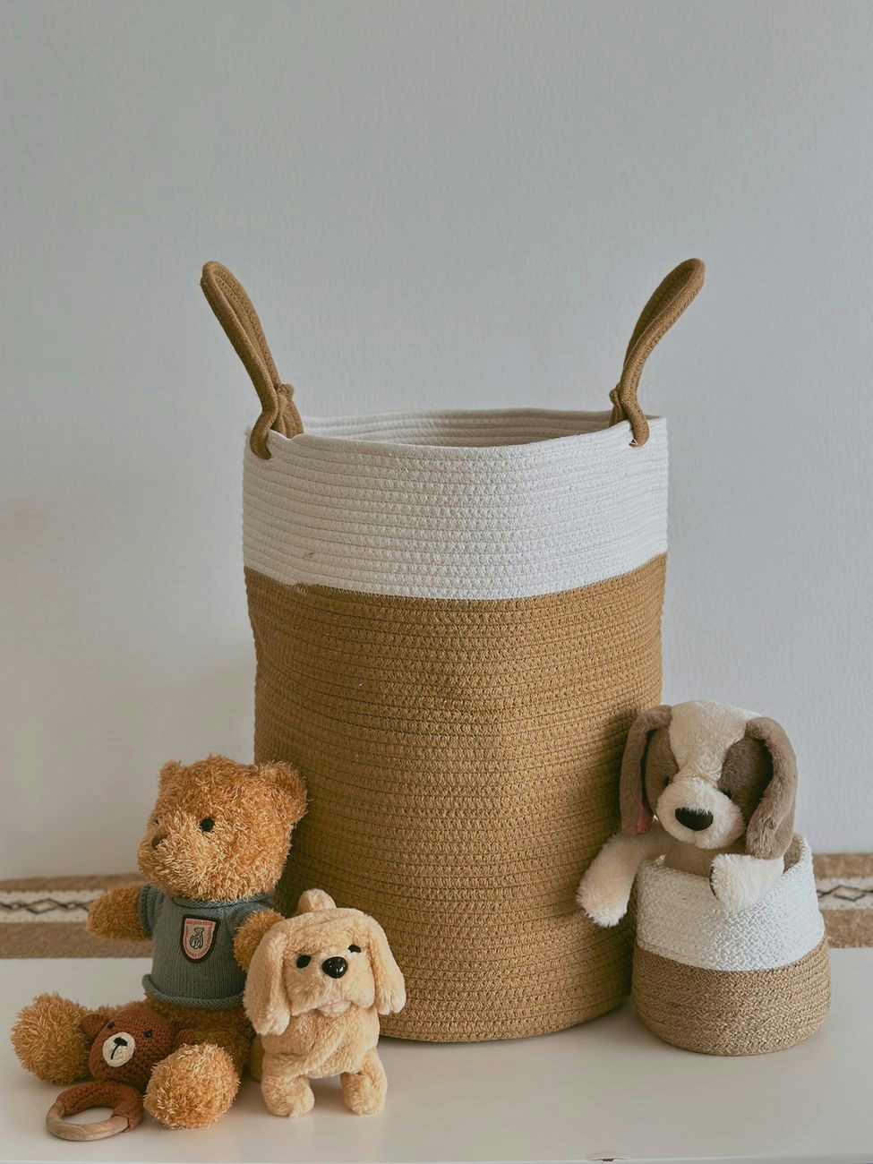 Handmade brown and white basket with teddy bear and plush dog toys on white background.