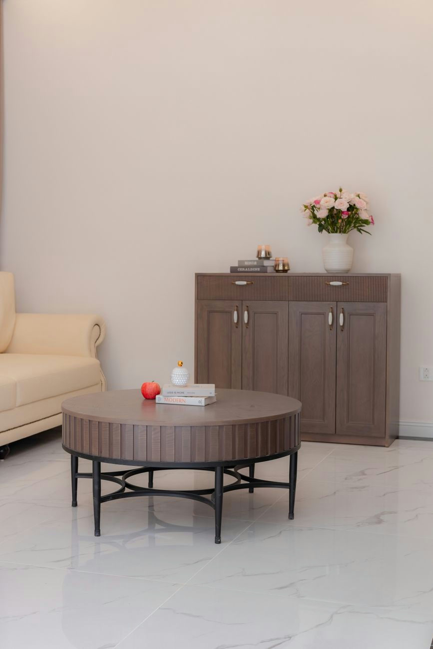 A cozy minimalist living room featuring a round table and stylish cabinet, perfect for modern homes.