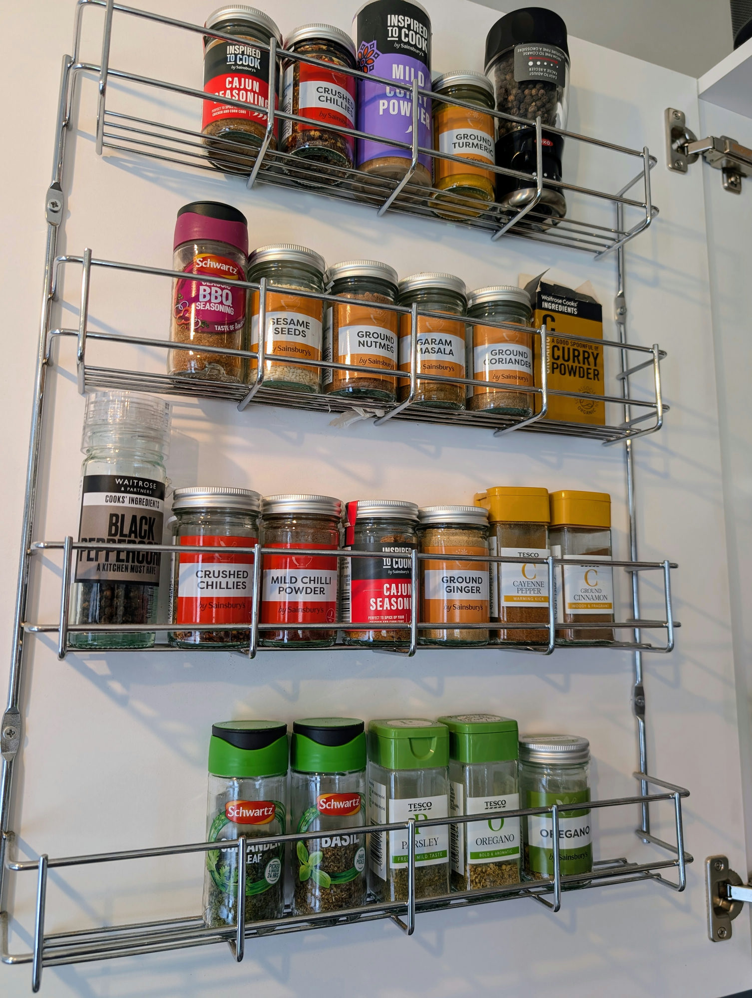 Over the door spice rack with lots of different spices on each shelf.