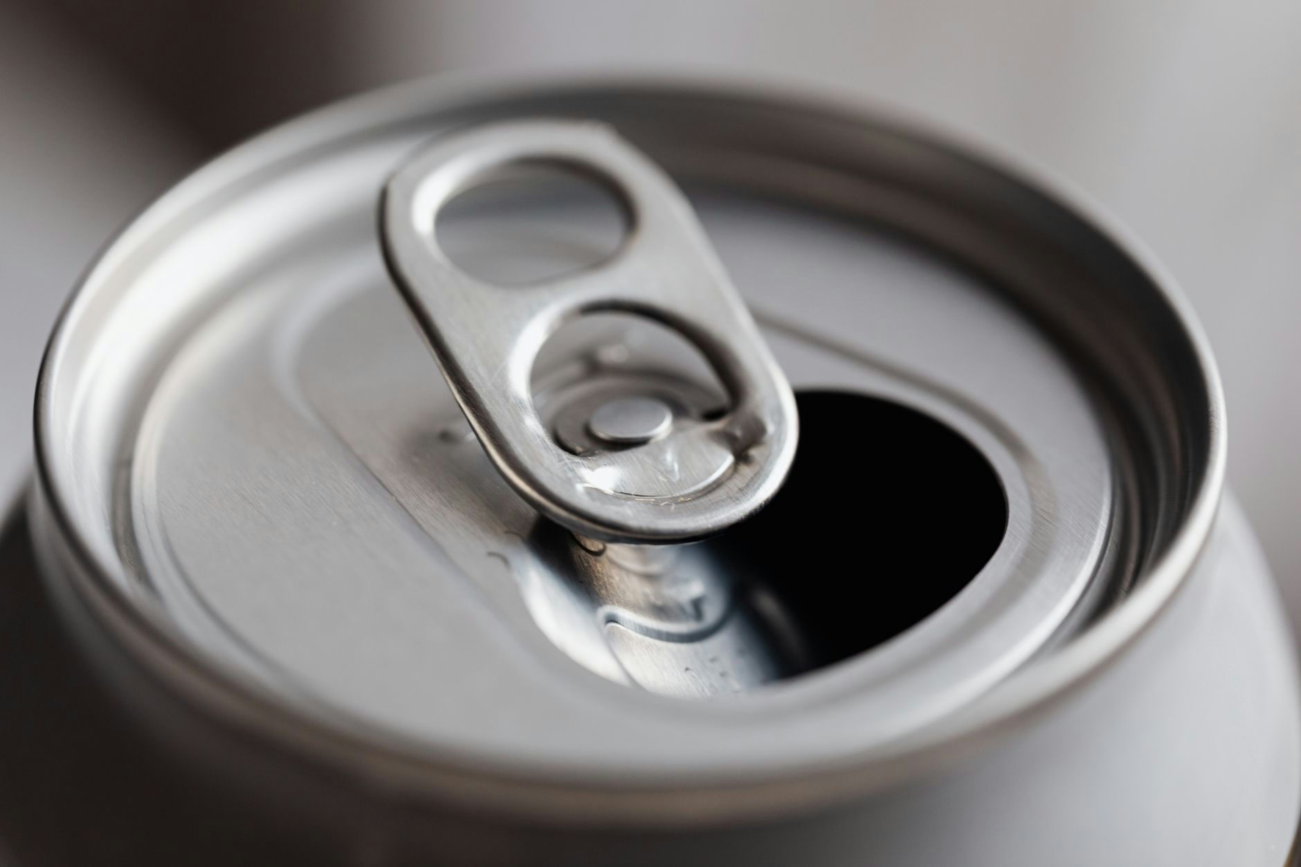 From above closeup of open wide mouth aluminum soft drink can on grey background