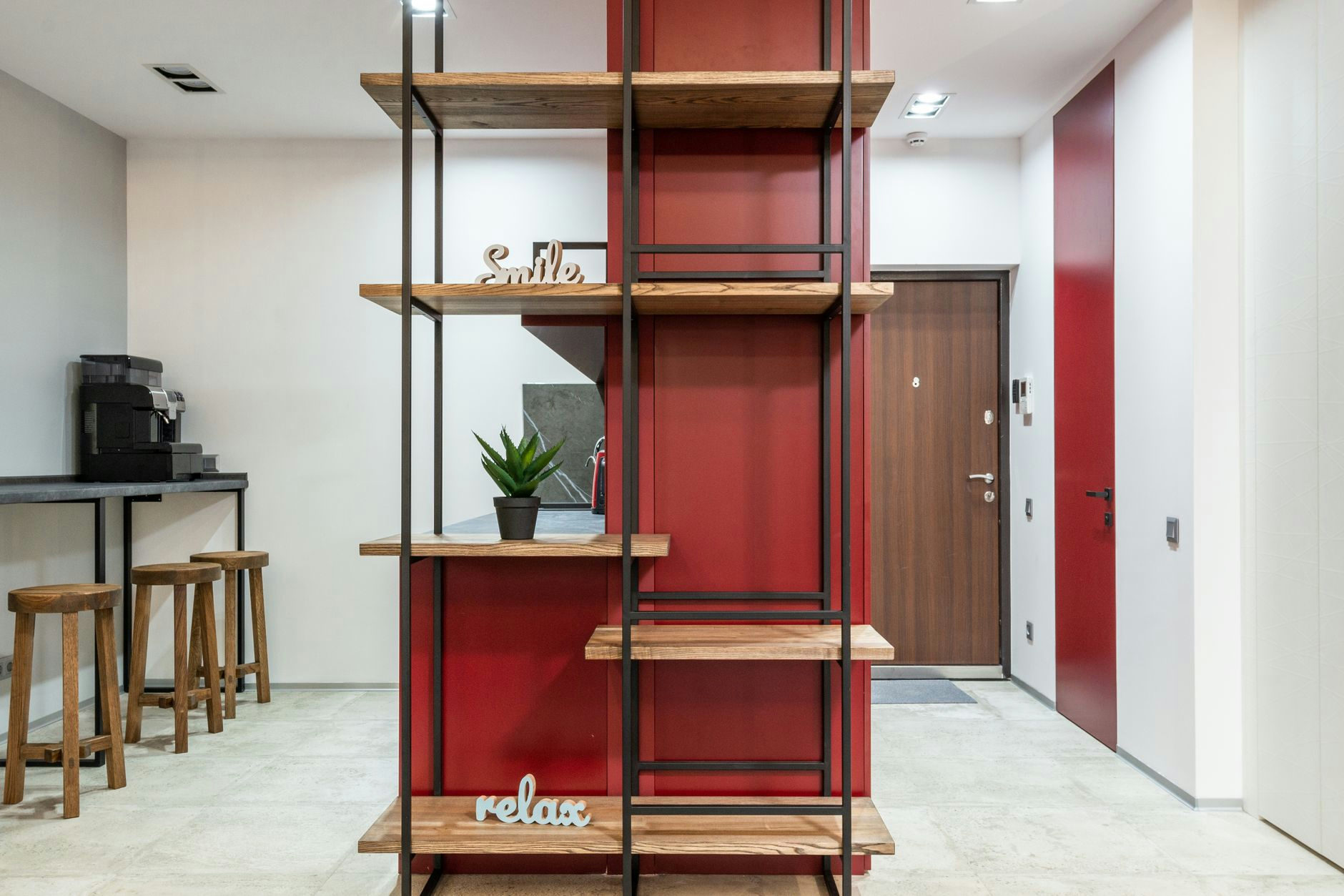 Interior of modern organization with wooden shelves with words smile and relax near potted cactus next to table with chairs