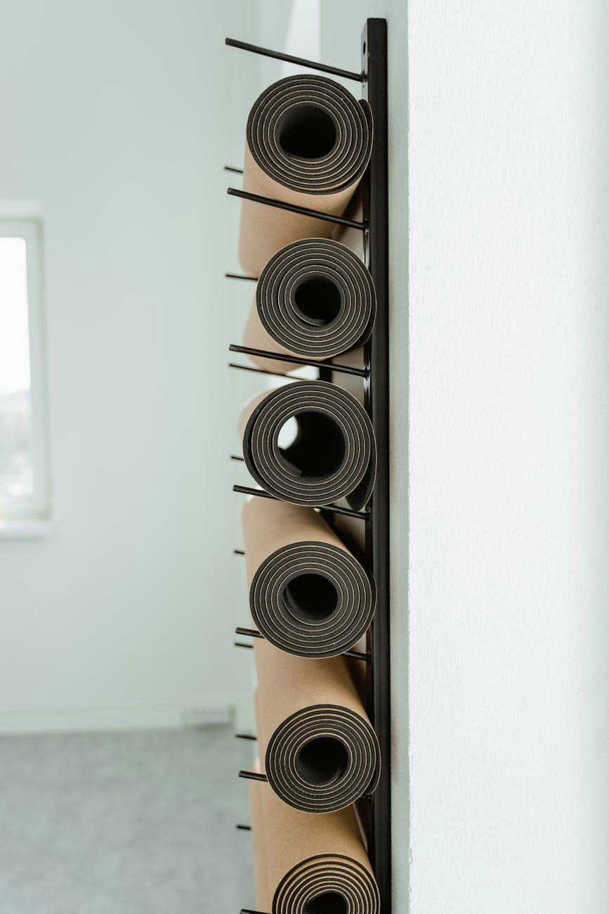 Close-up of neatly rolled yoga mats stored vertically on a rack in a studio.