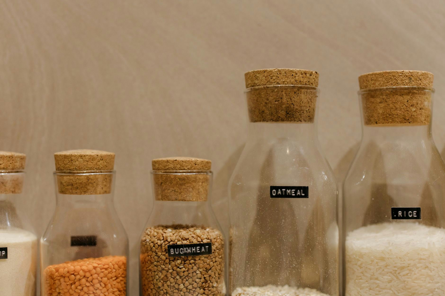 Close-up of various grains in labeled glass jars for kitchen storage.
