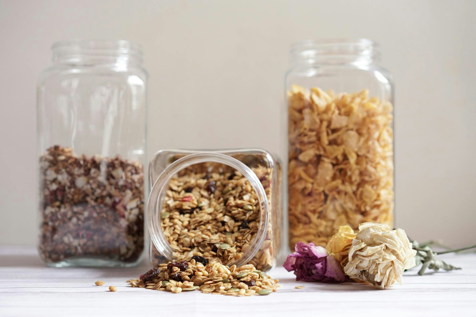 Neatly organized kitchen jars with muesli, oats, and cornflakes on a clean surface.
