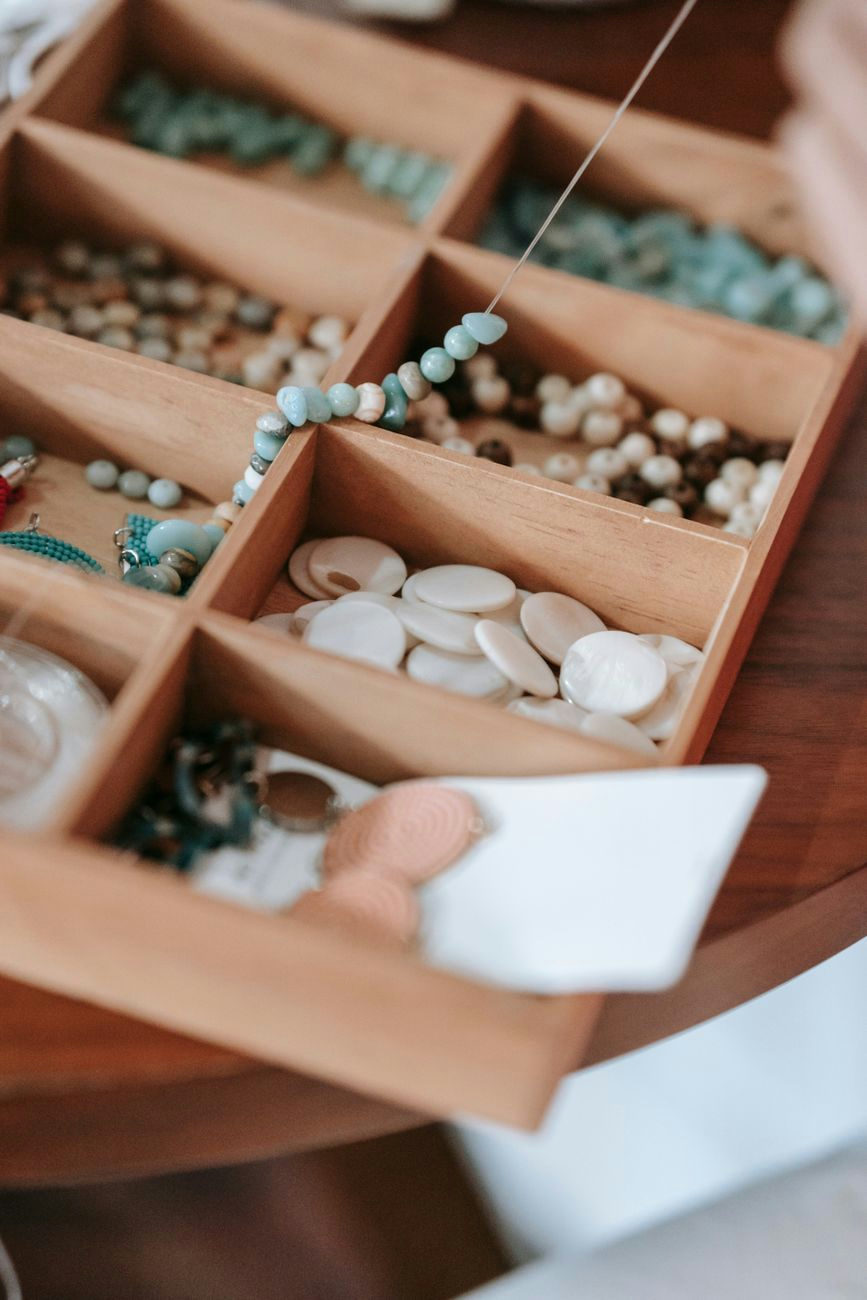 Kit for making bracelet with abundance of beads and elastic string placed on wooden table in light room at home