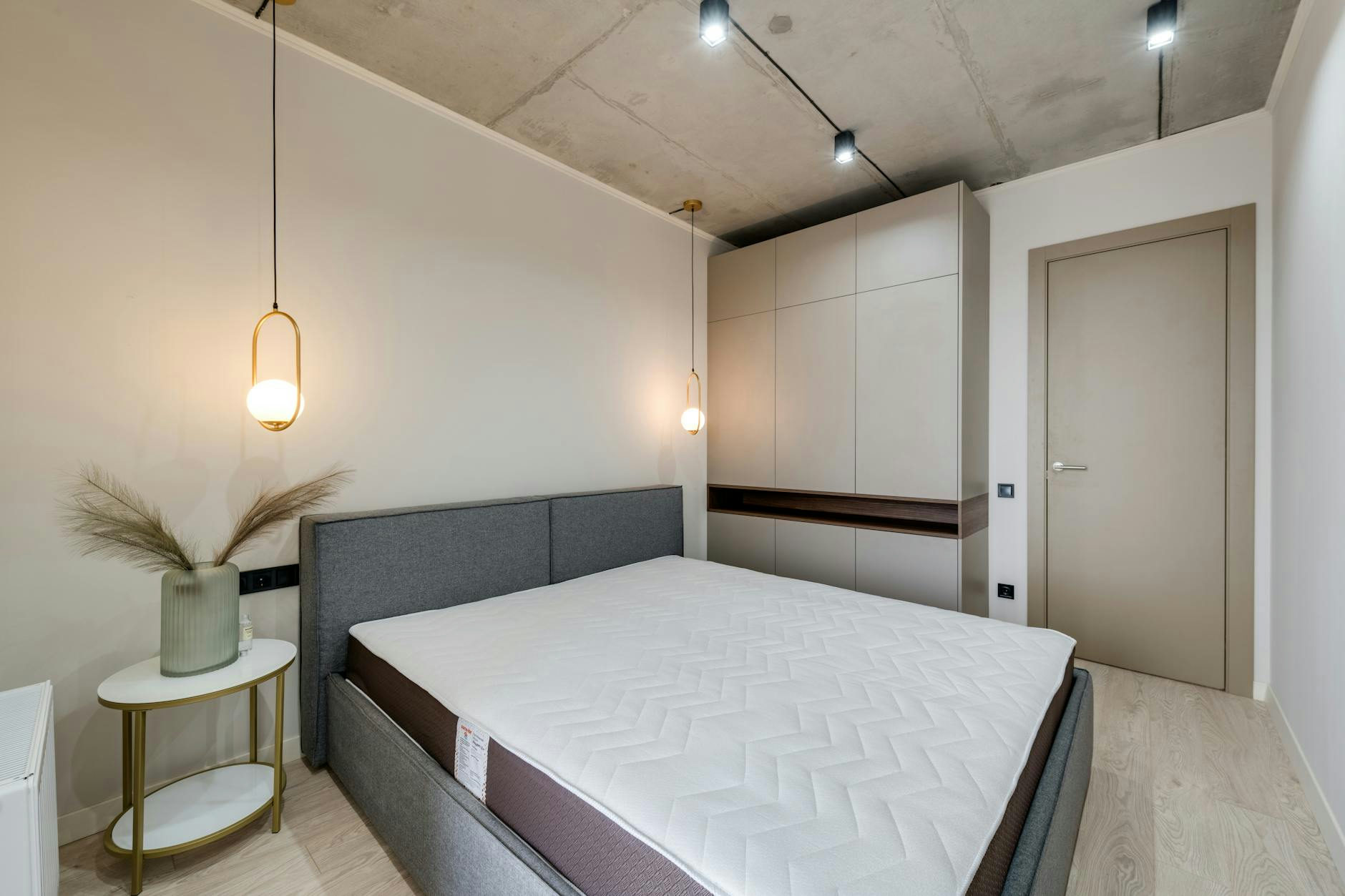 A minimalist bedroom featuring a gray bed, warm lighting, and sleek storage solutions.