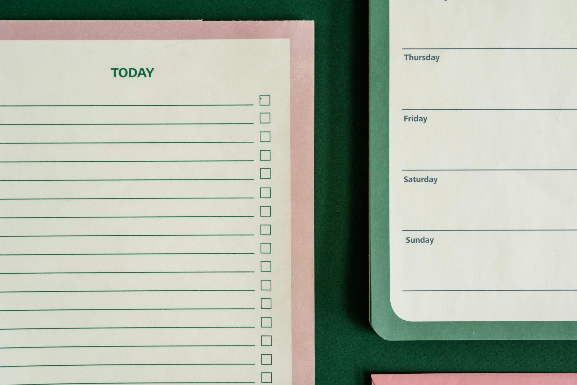 Flat lay of planners and stationery on a green background for organizing tasks and schedules.