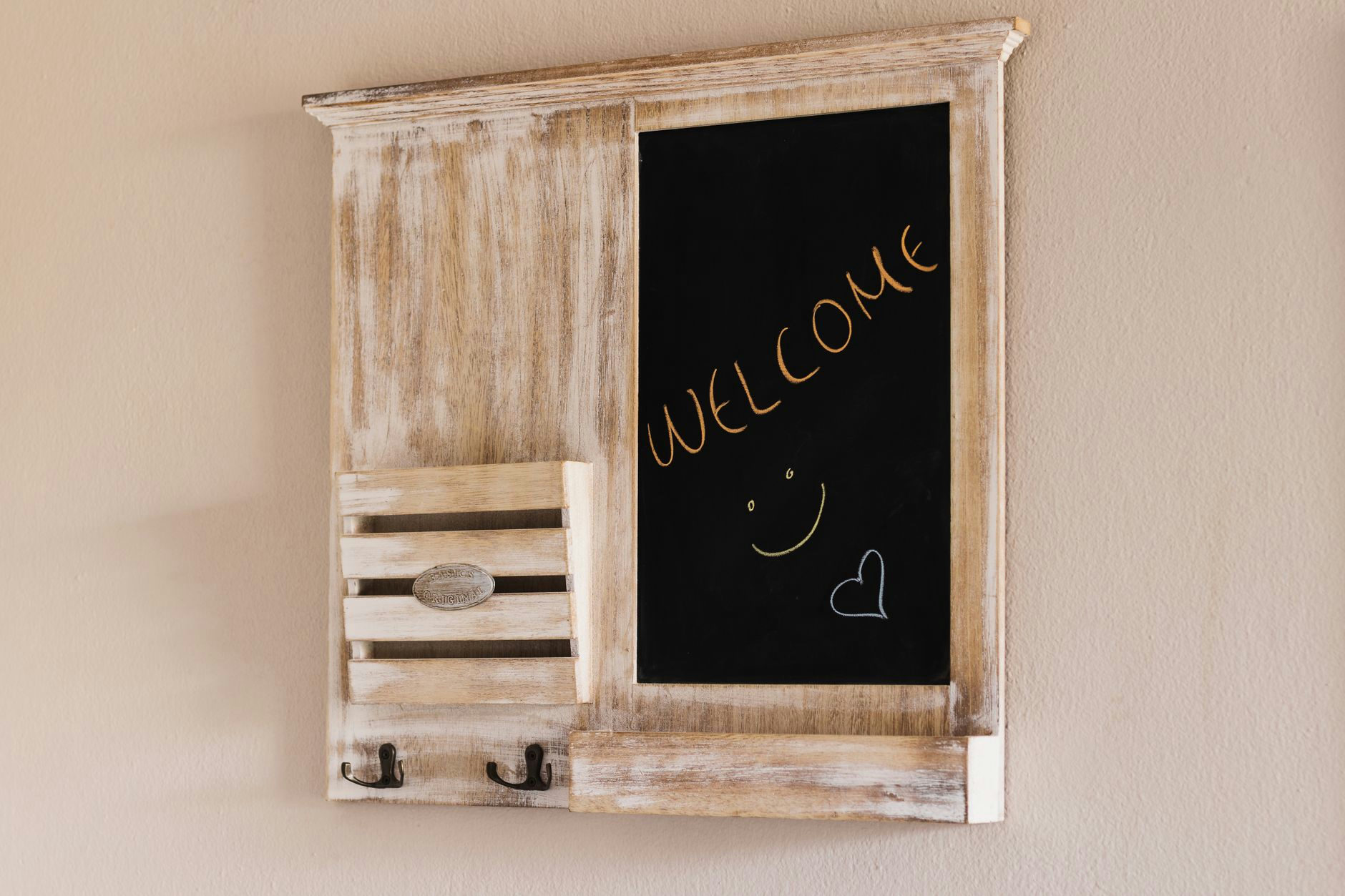 Decorative rustic chalkboard with 'Welcome' text on a beige wall, ideal for home decor.
