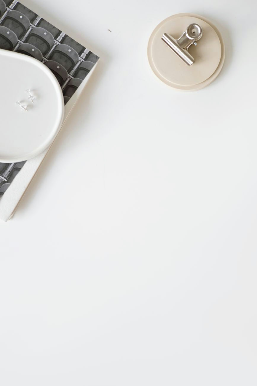 A minimalist flat lay of a clipboard and notebook on a white surface, ideal for business concepts.