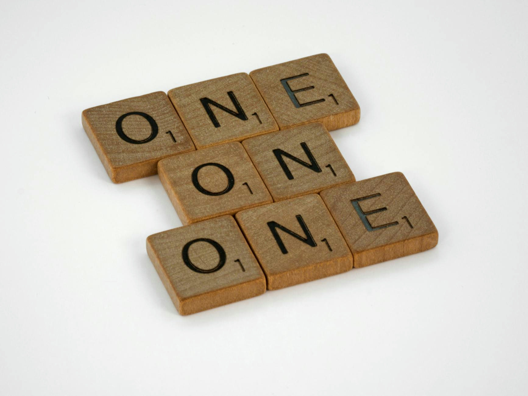 Scrabble letter tiles arranged to spell 'ONE' in a crossword style on a white background.